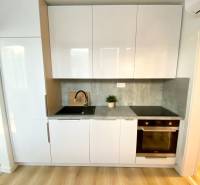 A kitchen unit with white cabinets, a gray countertop, and a floor with a wood decor, 2-room apartment.