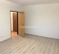 A room in a one-room apartment with white walls and a wooden decor floor.