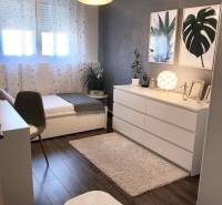 A room in a family house with a wooden decor floor, artistic paintings, and decorative flowers.