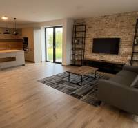 Living room with kitchen in a family house with a wooden decor floor and a brick wall.
