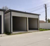 Garages in Michal na Ostrove with two open entrances, next to the road and the fence.