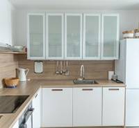 A kitchen in a 4-room apartment with a wooden decor floor and white cabinets.