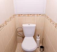A toilet with beige tiles and carpet in a 4-room apartment.