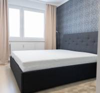 Bedroom in a 4-room apartment with a bed, wallpaper, windows, and curtains, floor with wooden decor.