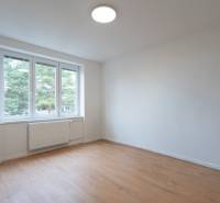 A spacious room with a large window and a wooden decor floor in a 3-room apartment.