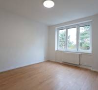 A spacious room with a large window and a wooden decor floor in a 3-room apartment.