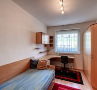 A room in a 3-room apartment with a bed, a desk, and a wooden decor floor.
