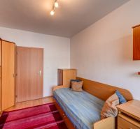 A room in a 3-room apartment with wardrobes, a bed, and wooden cabinets.