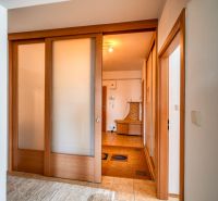 Interior of a 3-room apartment with sliding doors and a floor with a wooden decor.