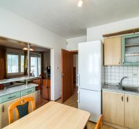 A kitchen in a 3-room apartment with a passage to the living room and a floor with a wooden decor.