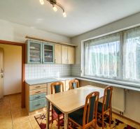 A kitchen in a 3-room apartment with a dining table, a wooden-patterned floor, and a large window.