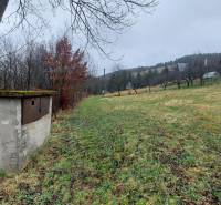 Green recreational plots in Púchov with views of the surrounding hills and trees.