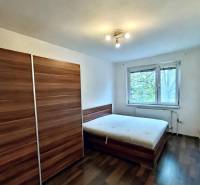 A bedroom with a wardrobe, bed, and wooden decor flooring in a 4-room apartment.
