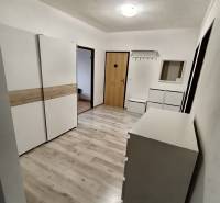 A hallway with white furniture and a wooden decor floor in a 4-room apartment.
