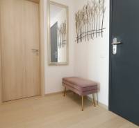 The entrance hall in a 2-room apartment with a wooden decor floor and a bench.