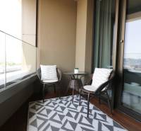 A balcony in a 2-room apartment with rattan furniture and a view of the city.