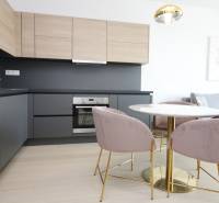 A kitchen in a 2-room apartment with a wood-patterned floor and a stylish table.
