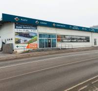 Commercial spaces on Kamenná Street in Žilina with advertising signs and an empty parking lot.