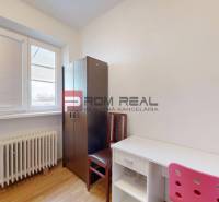 A room in a family house with a white table, an opaque chair, and a wardrobe.