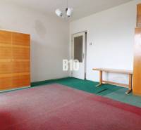 A room in a family house with carpets, two wardrobes, and a table.
