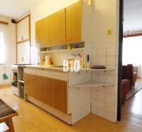 A kitchen in a family house with a wooden decor floor connected to the living room.