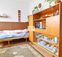A room in a family house with a bed, a display cabinet, and a floor with a wooden decor.