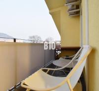 A balcony of a 4-room apartment in Žilina with chairs and a view of the mountains.