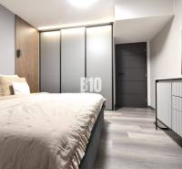 Bedroom with wood-patterned flooring and a wardrobe in a four-room apartment.