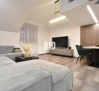 Living room in a 4-room apartment with a sofa, television, and wooden decor flooring.