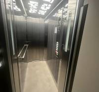 Elevator in a building with modern lighting and metal panels.
