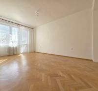 A spacious room with large windows and a wooden decor floor in a 3-room apartment.