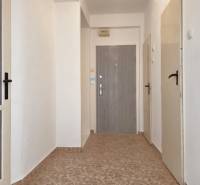 A hallway with tiles, white walls, and several doors in a 3-room apartment.