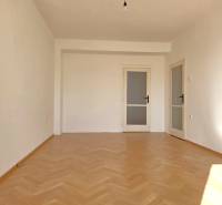A room in a 3-room apartment has a wooden decor floor and white walls.