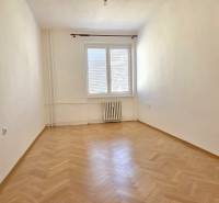 An empty room with a wood-patterned floor in a 3-room apartment, bright walls, radiator.