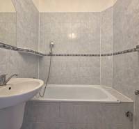 A bathroom with a bathtub in a 3-room apartment, tiled with light ceramic tiles.
