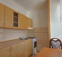 A kitchen with light furniture, a stove, and a table in a 3-room apartment.