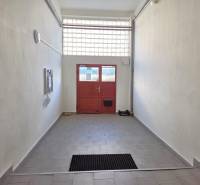 A hallway with tiles leading to red doors in a 3-room apartment.