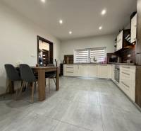A kitchen in light colors with built-in appliances and a dining table in a family house.