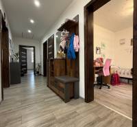 A hallway in a family house with a wooden decor floor, a work nook, and a coat rack wall.