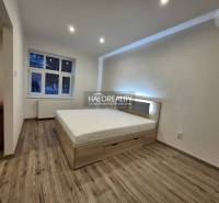 Bedroom in a 2-room apartment with a bed and a wooden decor floor.