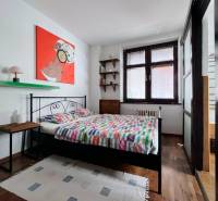 Bedroom in a 2-room apartment with a bed, painting, and floor with wood decor.