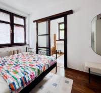 Bedroom in a two-room apartment with a bed and a mirror, floor with wooden decor.