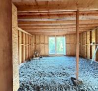 An unfinished interior of a cabin with a wooden structure and an opening for a terrace.