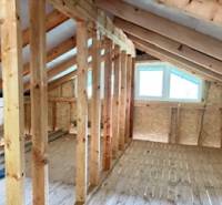 Attic with a window, wooden beams, and a floor with a wooden decor in a cottage.