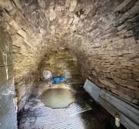 A stone cellar of a cottage with a vaulted ceiling and metal accessories.