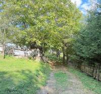The path to the cottage in Horná Mariková lined with trees and a fence.