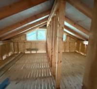 Attic space of the cottage with wooden beams and a floor with a wooden decor.