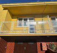 A family house in Nové Zámky on Nové Zámky Street with a balcony and brick cladding.