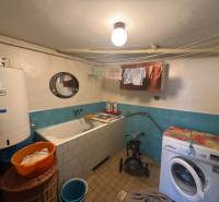 A bathroom in a family house with a bathtub, washing machine, and boiler, blue tiles.