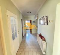 A hallway in a family house with a tiled floor and simple wall decorations.